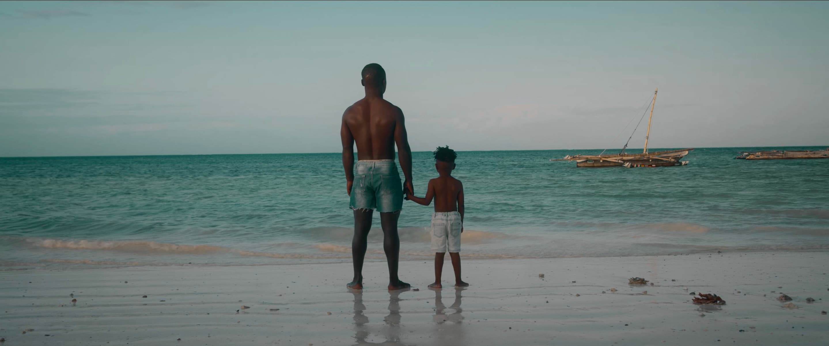 A father and his young son looking out at the ocean in Jambiani, Zanzibar