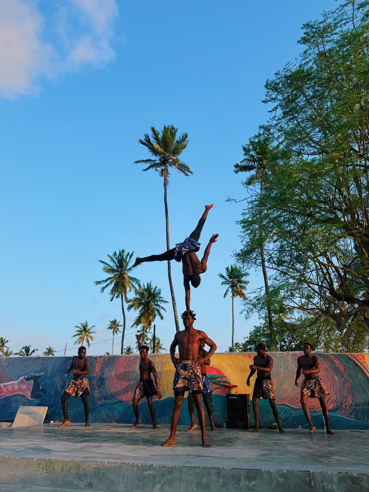 A Move Zanzibar acrobat balancing in a handstand on a teammate's shoulder, on the beach in Jambiani